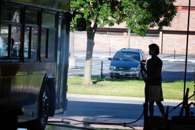 employee sprays a bus with a hose