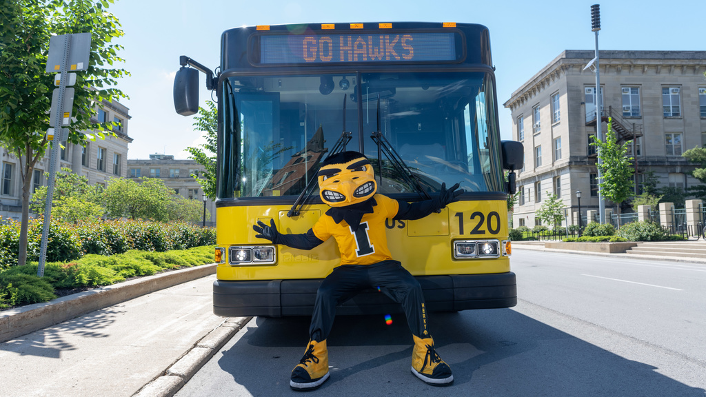 Herky mascot sitting on front bumper of bus
