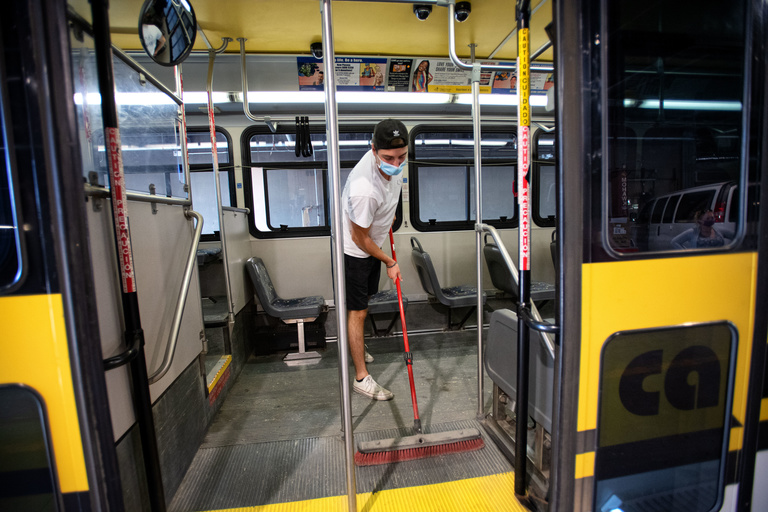 employee sweeps dust and debris off a bus