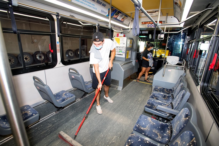 employee sweeps the floor of a bus
