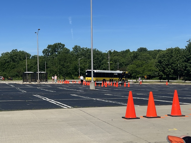 A bus maneuvers around cones in a parking lot