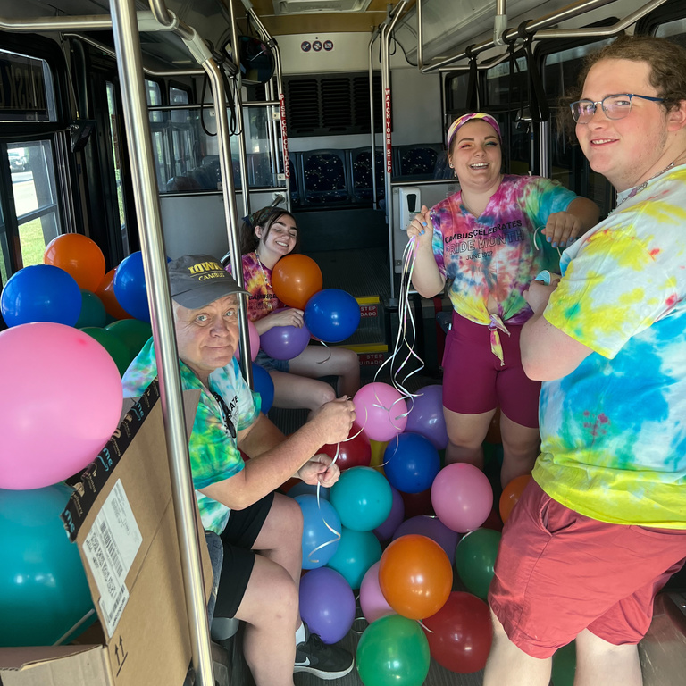 Student employees in a bus full of balloons for Pride Month