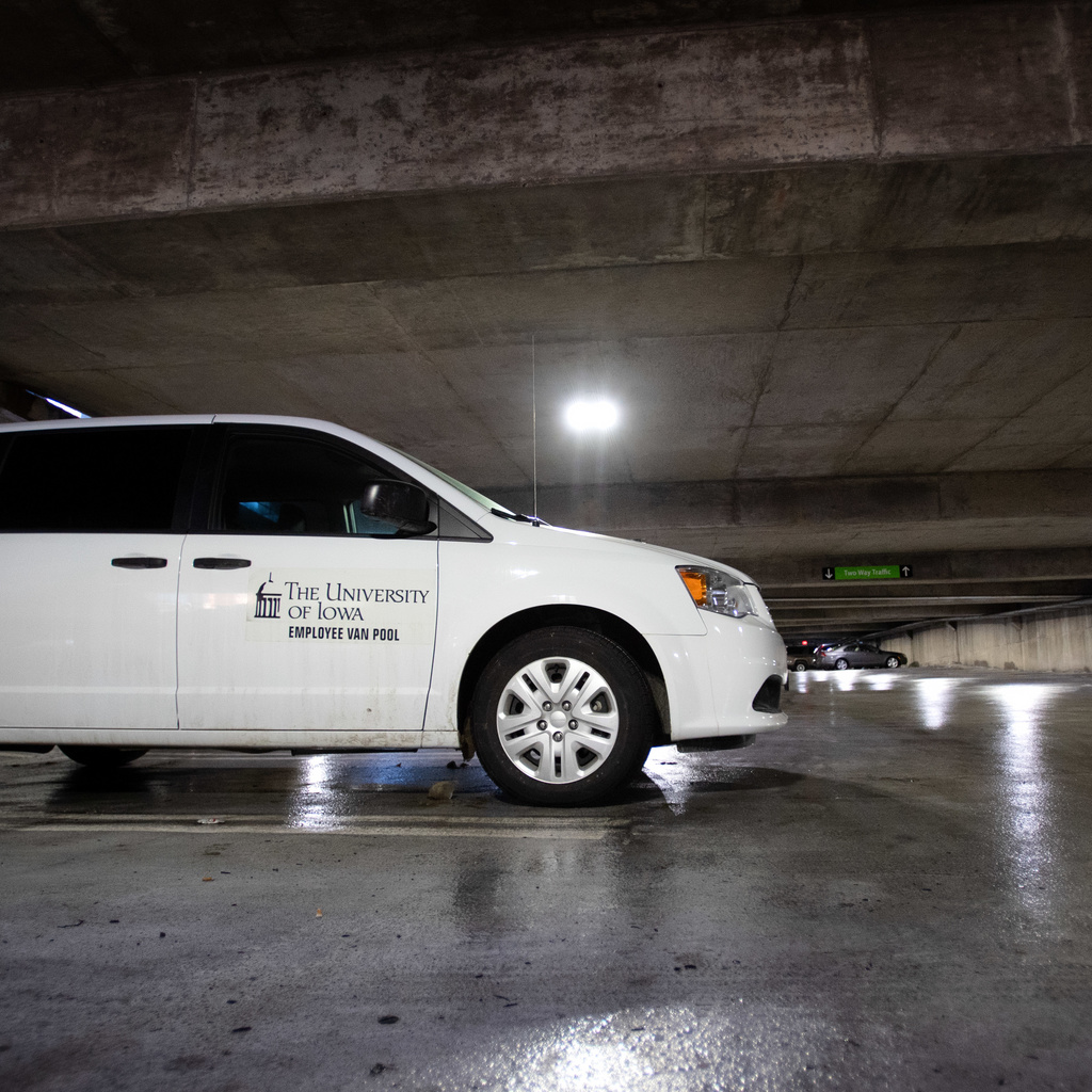 White van parked in parking ramp with graphic stating University of Iowa Employee Van Pool