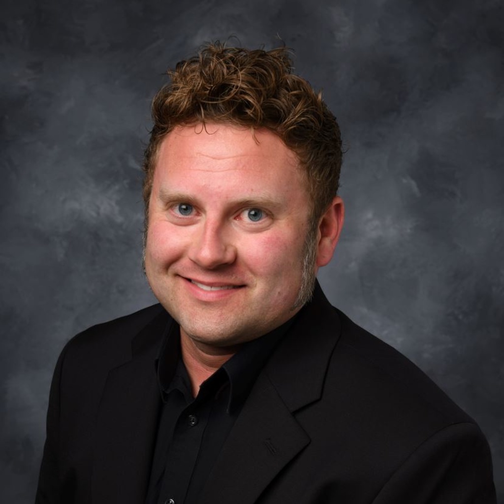 portrait photo of man, Greg, wearing black shirt and suit jacket
