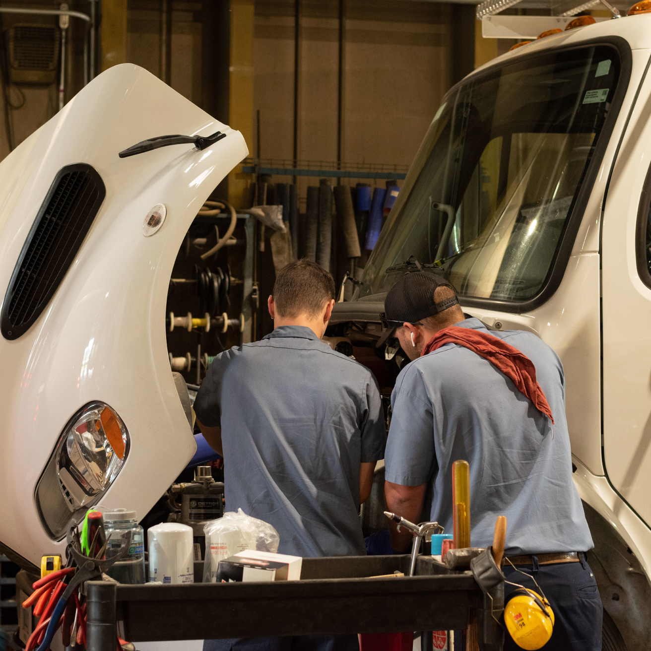 technicians Robert Bousek and Jamie Watson perform maintenance on a large truck