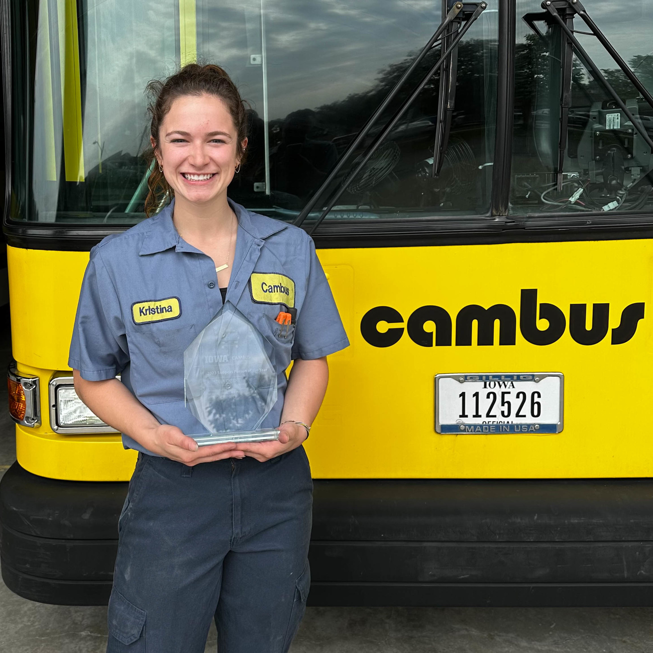 Kristina Dibert poses with her award in front of a CAMBUS