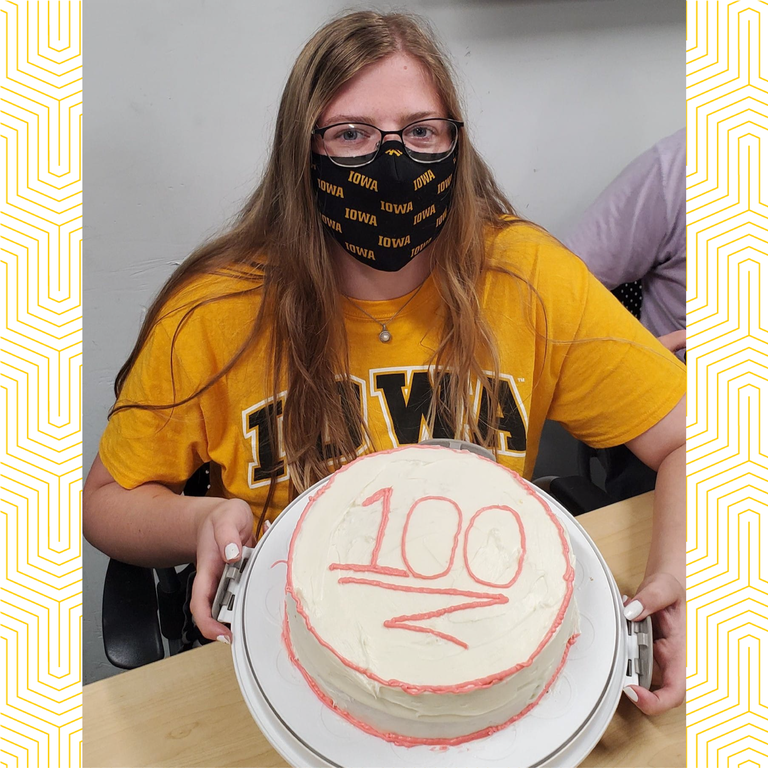 Alison Shoppa holds a cake with the number 100 on it