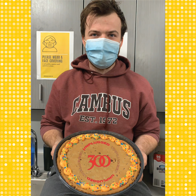 Nick holds a cookie cake with the number 300 on it