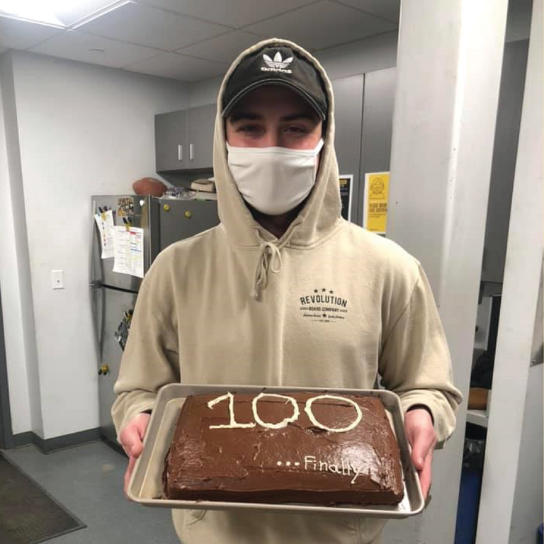 Tristan holds a cake that says "100"