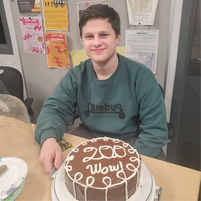 cambus dispatcher luke doyle poses for a photo with a cake that reads "200 wow!"