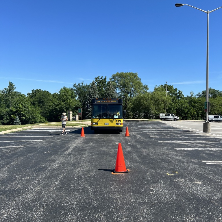A bus maneuvers around cones in a parking lot