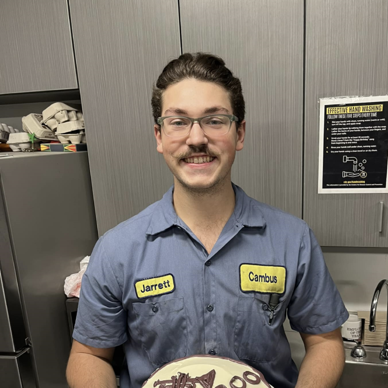 student mechanic Jarrett West poses with a cake