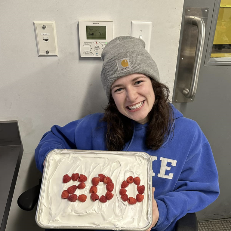 student mechanic Kristina poses with a cake