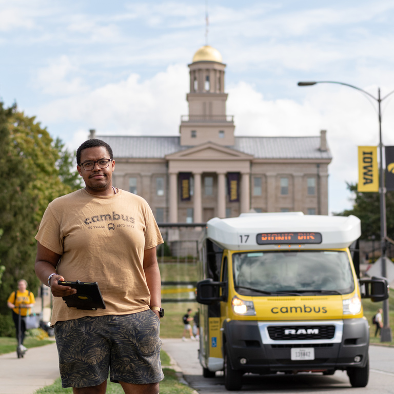 Driver Darshaun poses in front of a minibus. The old capital is seen in the background.