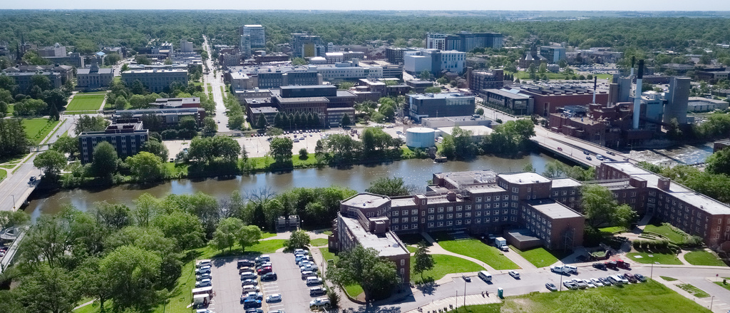 drone image of campus with parking lot in foreground, then Iowa River, and then main campus and Pentacrest in background
