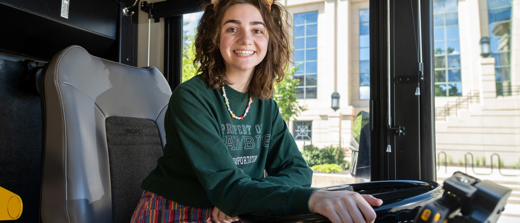 student poses in CAMBUS driver's seat