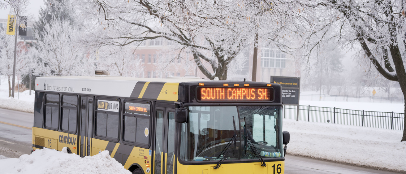 A cambus is shown driving on a road. Snow covers the surrounding areas.