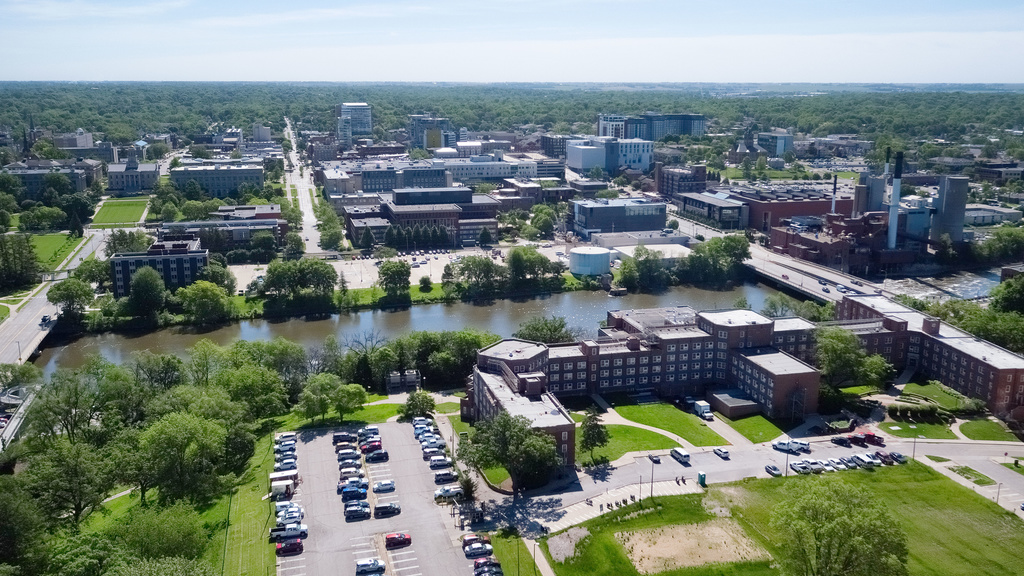 drone image of campus with parking lot in foreground, then Iowa River, and then main campus and Pentacrest in background