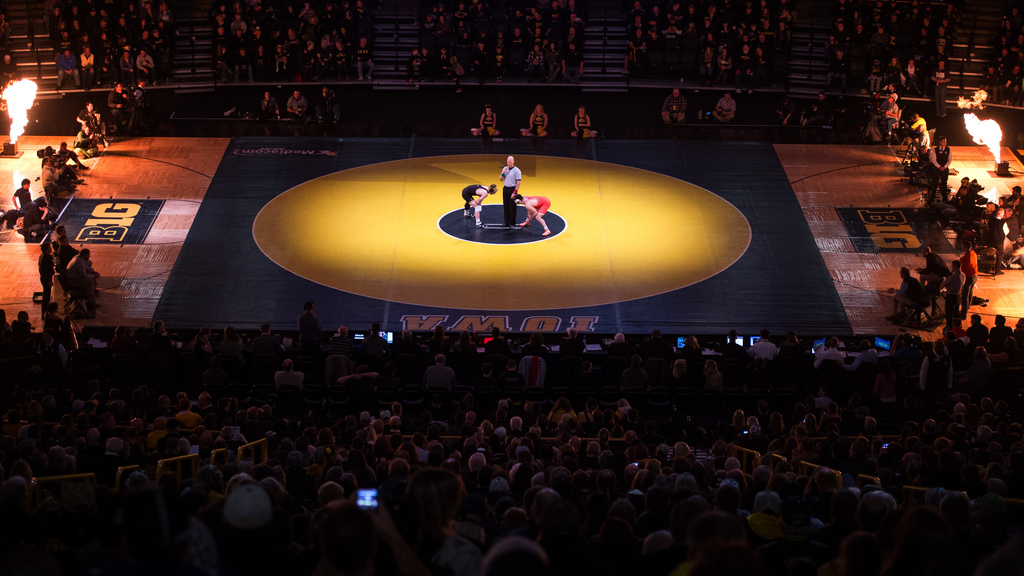 two men meet in center of arena floor with spotlight to begin wrestling 
