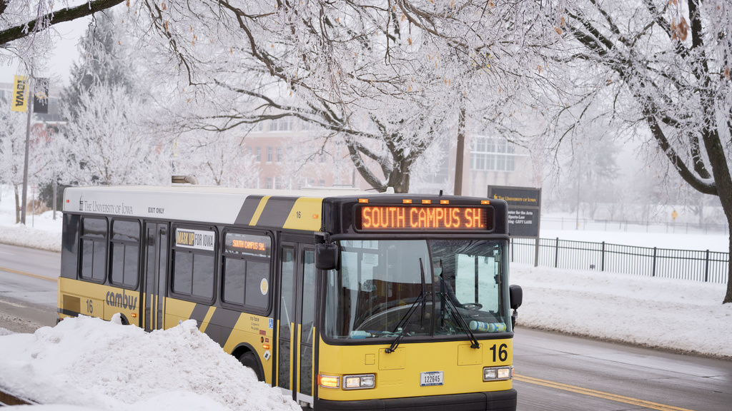 A cambus is shown driving on a road. Snow covers the surrounding areas.