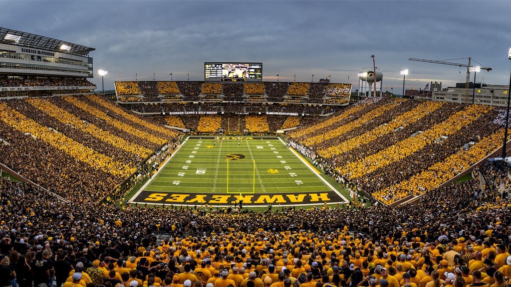 football stadium with fans in sections of black and gold clothing forming stripes