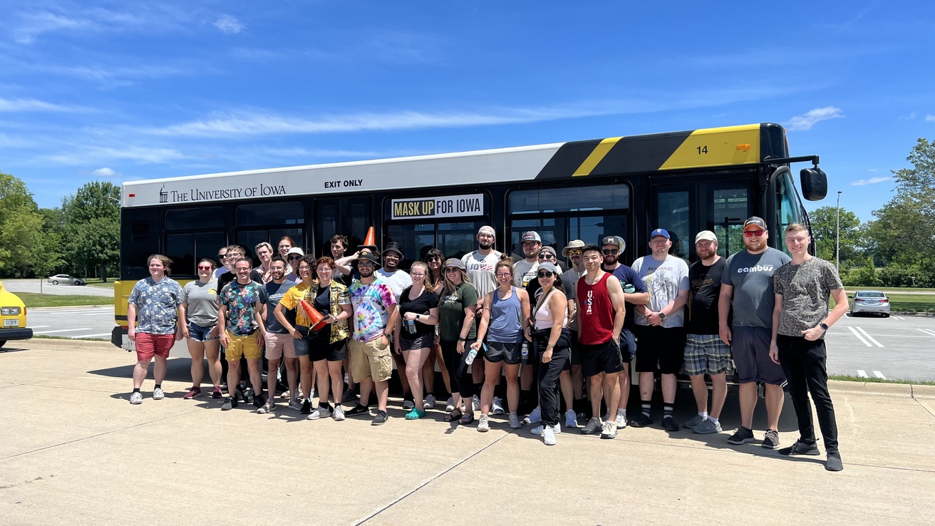 Group of CAMBUS student employees pose in front of a bus