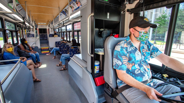 CAMBUS driver driving a bus with passengers seated behind him